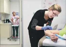  ?? Christina House For The Times ?? A WORKER inserts a birth control implant in a patient at a Planned Parenthood clinic in L.A. Nearly 90% of the group’s patients in the state are low-income.