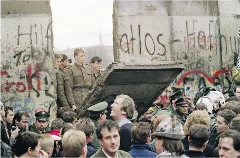  ?? GERARD MALIE / AFP / GETTY IMAGES FILES ?? West Berliners crowd in front of the Berlin Wall early on Nov. 11, 1989, as they watch East German border guards demolishin­g a section of the wall in order to open a new crossing point between East and West Berlin.
