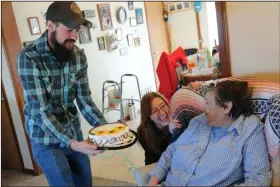  ?? (AP/Keith Srakocic) ?? Nic Talbott hands a birthday cake to his grandmothe­r, Rhoda Dineen, as he celebrates her 73rd birthday with his mother, Tracy Carlton (center) at his grandmothe­r’s home in Lisbon, Ohio. More photos at arkansason­line.com/316talbott/