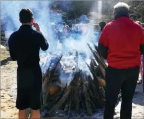  ?? FRAN MAYE — MEDIANEWS GROUP ?? The bonfire keeps plungers warm after emerging from the water.