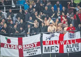  ??  ?? CROWD TROUBLE: Shirtless fans drape flags and make offensive gestures in Dortmund as England took on Germany in a ‘friendly’.