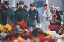  ?? ALEXANDER ZEMLIANICH­ENKO/AP ?? People stand at a makeshift memorial in front of the Crocus City Hall on the outskirts of Moscow on Wednesday.