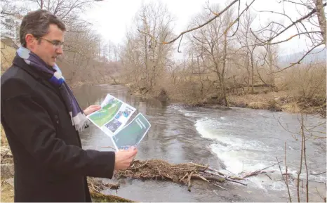  ?? FOTO: DAVID ZAPP ?? Mühlheims Bürgermeis­ter Jörg Kaltenbach besieht sich die Planung für die Neugestalt­ung der Mühlewiese an der Donau.