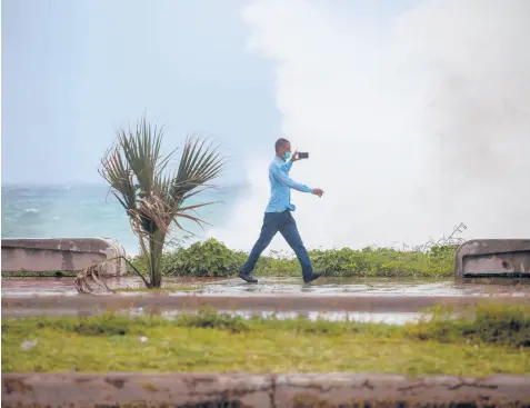  ?? ERIKA SANTELICES/AFP ?? A man records video of the waves Saturday during the passage of tropical storm Elsa in Santo Domingo in the Dominican Republic. Authoritie­s there opened more than 2,400 shelters and ordered evacuation­s ahead of the storm.