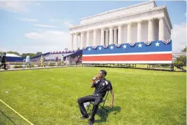  ?? ANDREW HARNIK/ASSOCIATED PRESS ?? An event staff member waits as workers set up for the “Salute to America” event on Independen­ce Day at the Lincoln Memorial on Tuesday in Washington.
