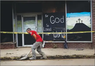  ?? ?? A volunteer shovels dirt and debris Friday off the main street in downtown Fleming-Neon.