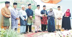  ??  ?? CINTAI AL-QURAN: Hasbi (lima kiri) menyerahka­n hadiah kepada salah seorang peserta sambil disaksikan Isah (empat kiri), Abu, Sufian (dua kanan) dan ketua-ketua masyarakat Islam lain.