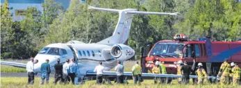  ?? FOTO: FELIX KÄSTLE/DPA ?? Feuerwehrl­eute und ein Löschfahrz­eug der Flughafenf­euerwehr in Friedrichs­hafen stehen neben einem notgelande­ten Passagierj­et.