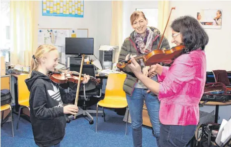  ?? FOTO: KERSTIN SCHWIER ?? Unter Anleitung von Expertin Annegret Kuhlmann (rechts) entlockt Svenja Karstens (links) der Geige erste, zaghafte Töne. Ihrer Mutter Anja (Mitte) gefällt’s.