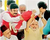  ??  ?? Prime Minister Narendra Modi holds a child while meeting family members of former President A.P.J Abdul Kalam during the inaugurati­on of a memorial at Peikarumbu in Rameswaram, Tamil Nadu, on Thursday. Kalam’s elder brother Mohammed Muthu Meera Lebbai...