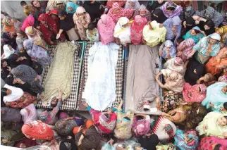  ??  ?? IN MOURNING: Pakistani women gather around the bodies of their relatives who were killed in a Sunday suicide bombing, in Lahore, on Monday. (AP)