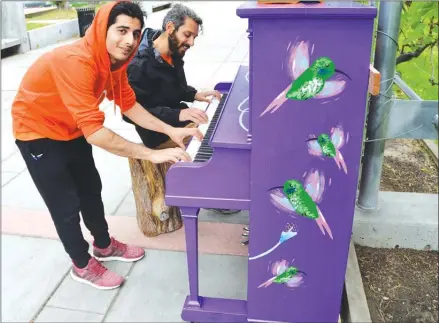  ?? RON SEYMOUR/The Daily Courier ?? Sina Estaki, left, and Antreas Pogiatzis play a butterfly-covered piano in the Artwalk, between the courthouse and the library parkade, on Tuesday in downtown Kelowna.