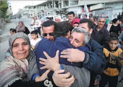  ?? OMAR SANADIKI / REUTERS ?? Relatives hug one of the hostages held by Islamic State militants who escaped from his captors in Homs, Syria, on Sunday.