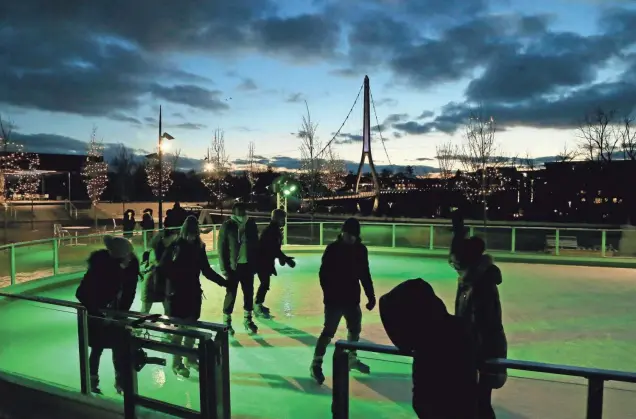  ?? BARBARA J. PERENIC/COLUMBUS DISPATCH ?? As the sun sets on a recent Friday evening, skaters work their way around the outdoor ice rink at Riverside Crossing Park in Dublin.