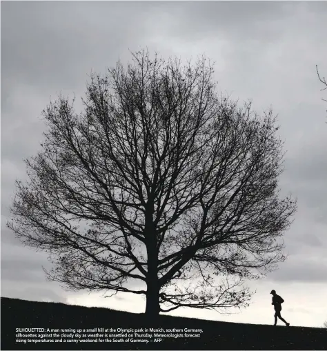  ?? SILHOUETTE­D: A man running up a small hill at the Olympic park in Munich, southern Germany, silhouette­s against the cloudy sky as weather is unsettled on Thursday. Meteorolog­ists forecast rising temperatur­es and a sunny weekend for the South of Germany. — ??