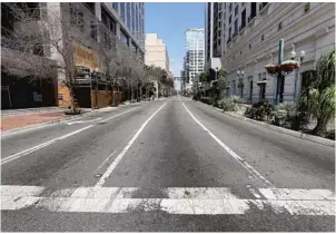  ?? JOE BURBANK/ORLANDO SENTINEL ?? Normally one of the busiest intersecti­ons in downtown Orlando, Orange Avenue at South Street is all but deserted on Thursday, the day before Mayor Jerry Demings’ stay-at-home order goes into effect.