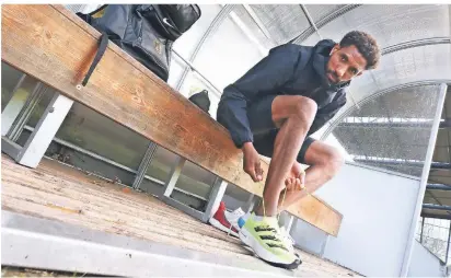  ?? FOTO: ROLAND WEIHRAUCH/DPA ?? Der deutsche Marathonlä­ufer Amanal Petros vom TV Wattensche­id zieht sich beim Training im Olympia-Stützpunkt seine Carbon-Laufschuhe an.