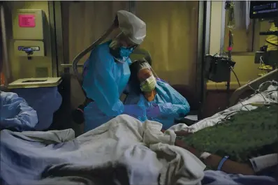  ?? JAE C. HONG — THE ASSOCIATED PRESS FILE ?? Romelia Navarro, right, is comforted by nurse Michele Younkin as she weeps while sitting at the bedside of her dying husband, Antonio, in St. Jude Medical Center’s COVID-19 unit in Fullerton.