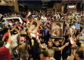  ?? HADI MIZBAN — THE ASSOCIATED PRESS ?? Followers of Shiite cleric Muqtada al-Sadr, seen in the posters, celebrate after the preliminar­y results of the parliament­ary elections are announced, in Tahrir Square, Baghdad, Iraq, early Monday.