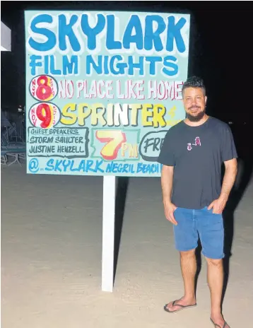  ??  ?? Negril native Storm Saulter, who wrote and produced the Jamaican film ‘Sprinter,’ photograph­ed next to a billboard promoting the Skylark Film Nights.