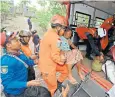  ??  ?? An elderly woman is helped to safety