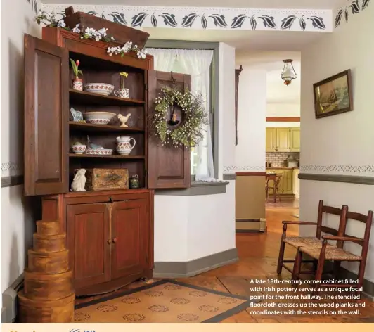  ??  ?? A late 18th-century corner cabinet filled with Irish pottery serves as a unique focal point for the front hallway. The stenciled floorcloth dresses up the wood planks and coordinate­s with the stencils on the wall.