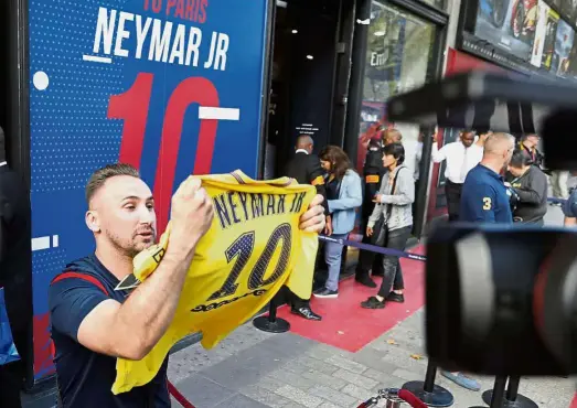  ?? — Reuters ?? Huge hype: A fan leaves a Paris St Germain sports boutique with a new Neymar jersey in Paris, France, yesterday.