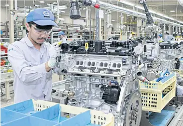  ??  ?? A worker at MPMT assembles an engine incorporat­ing Mazda’s SkyActiv technology.