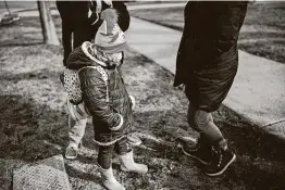  ?? Lucy Hewett / New York Times ?? Sadie Santiago, 5, waits as her mother, Laura, confers with a teacher in Chicago. Women have dropped out of the U.S. workforce at a faster pace in states where most students are learning from home, according to a new study.