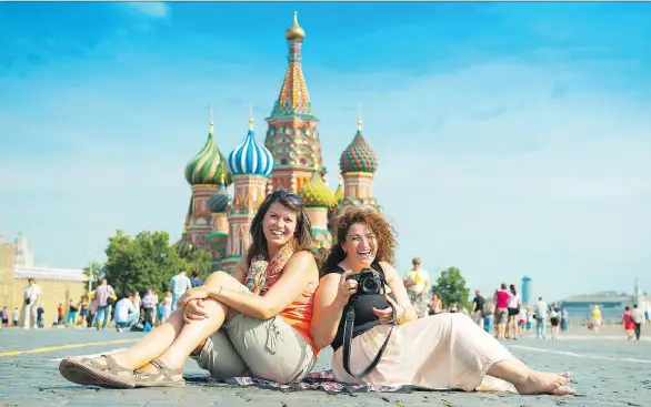  ?? GETTY IMAGES ?? Tourists pose for photos in Red Square in Moscow, Russia. In the background is St. Basil’s Cathedral, ordered built by Ivan the Terrible and dating back to 1560.