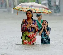  ?? AFP file ?? People wading through a flooded street during heavy rain showers in Mumbai. —