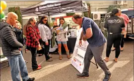  ?? ?? Eric Sanders, left, of Skoden Native Harm Reduction Services, spins a prize wheel for Bishop Mayor Pro Tem Jose Garcia during Crossroads Recovery Center’s grand opening in Bishop last month.