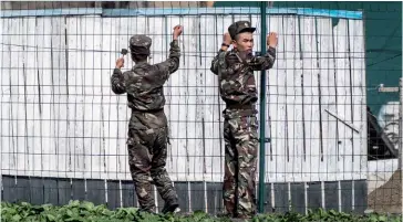  ??  ?? Photo ci-dessus : Le 7 aout 2017, des soldats nord-coréens surveillen­t les grillages le long de la frontière avec la Chine. Si de nombreux observateu­rs estiment que la Chine détient la clé de l’essoufflem­ent du régime nord-coréen, avec qui elle pourrait fermer sa frontière, Pékin ne peut pas se permettre de risquer des troubles sociaux dans une région où quelque trois millions de Chinois d’ethnie coréenne vivent principale­ment du commerce avec Pyongyang. (© Shuttersto­ck/ Stefan Bruder)