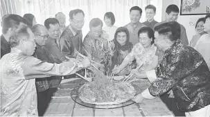  ??  ?? TRADISI: Abang Johari (tengah), Juma’ani (tiga kanan) serta para kenamaan lain ketika menyempurn­akan upacara menggaul ‘Yee Sang’ di kediaman Henry Lau (empat kiri).