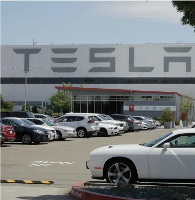  ?? ASSOCIATED PRESS ?? Vehicles are seen parked at the Tesla car plant Monday, May 11, 2020, in Fremont, Calif. The parking lot was nearly full at Tesla’s California electric car factory Monday, an indication that the company could be resuming production in defiance of an order from county health authoritie­s.