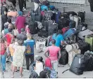  ?? PAUL CHIASSON THE CANADIAN PRESS ?? Asylum seekers line up outside Olympic Stadium near Montreal last August. Border security officers are being diverted to help with an anticipate­d influx this summer.