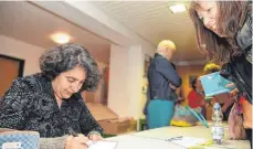  ?? .FOTO: SUSI DONNER ?? Mehrnousch Zaeri-Esfahani, die hier eines ihrer Bücher signiert, erzählt im Gemeindesa­al der evangelisc­hen Christuski­rche über die Flucht ihrer Familie aus dem Iran.
