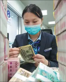  ?? XU JINGBAI / FOR CHINA DAILY ?? A teller counts cash at a bank in Hai’an, Jiangsu province.