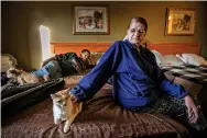  ?? ?? Former Santa Clara Apartment resident Michelle Sandoval pets her cat Mousey on Friday as she and her fiancé Johnny Trujillo camp out in their motel room at the Roadway Inn in Española.