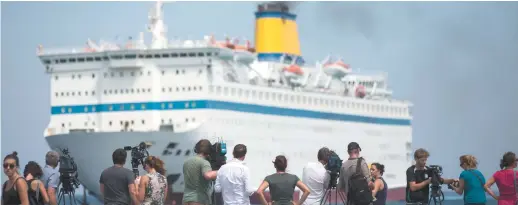  ?? Associated Press: Alexander Zemlianich­enko ?? Des journalist­es surveillen­t l’arrivée du traversier Eleftherio­s Venizelos à l’île de Kos. -
