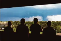  ?? Kenneth Ferriera/Lincoln Journal Star via Associated Press ?? A group of people watch a tornado from the seventh floor of a parking garage on Friday in Lincoln, Neb.