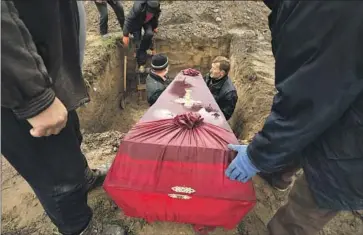  ?? Carolyn Cole Los Angeles Times ?? THREE FAMILY members are buried together April 22 in Bucha, Ukraine. Russia’s slaughter of civilians in Bucha is believed to have been aided by local Ukrainians who shared informatio­n with Russian invaders.