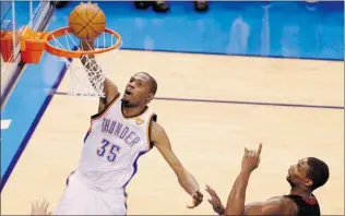  ?? MIKE STONE/ REUTERS ?? Oklahoma City Thunder forward Kevin Durant dunks on Miami Heat forward Chris Bosh. The Thunder and Heat split the first two games of the NBA Finals. Game 3 is Sunday in Miami at 5 p. m.