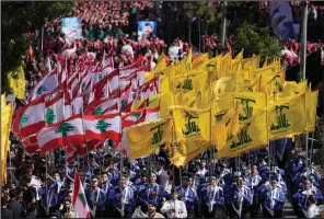  ?? (AP/Hussein Malla) ?? Lebanese Shiite scouts of the Iranian-backed Hezbollah group carry their group and Lebanese flags Tuesday as they march during the holy day of Ashoura in the southern suburb of Beirut.