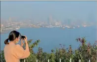  ?? PHOTO: CNA ?? A woman takes a photograph of Kaohsiung’s skyline, which is obscured by smog in an undated photograph.