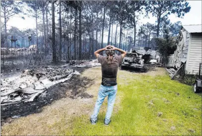  ?? Mark Wallheiser ?? The Associated Press file Faron Bryant looks over his property Monday after wildfires swept through his neighborho­od on Ridge Road in Eastpoint, Fla. Bryant’s home only lost its siding, but his workshop, a truck and boat were destroyed.