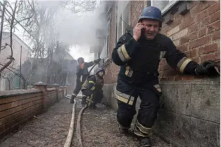  ?? (AP Photo/evgeniy Maloletka) ?? A rescue worker speaks on the phone while his team puts out a fire in a house that was shelled by Russian forces Friday at the residentia­l neighbourh­ood in Kostiantyn­ivka, Ukraine.