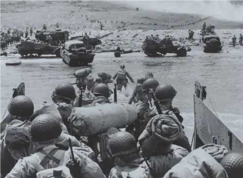  ??  ?? 0 American assault troops and equipment land on Omaha beach in 1944