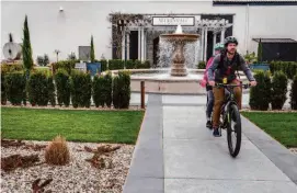  ?? Lacy Atkins/The Chronicle ?? Ryan Gall and Mika Leonard pedal their bicycles outside Merryvale Vineyards in St. Helena, which often offers live music.