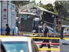  ?? DAMIAN DOVARGANES/AP ?? Officers walk past the remains of a Los Angeles Police Department tractor-trailer.